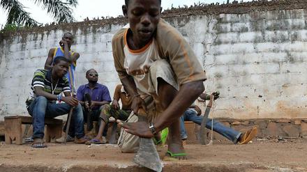 Angehörige der christlichen Anti-Balaka-Milizen in der zentralafrikanischen Hauptstadt Bangui. Einer schärft seine Machete an einem Stein. 