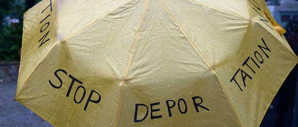 Regenschirm mit Protest-Slogan gegen Abschiebung von Flüchtlingen.