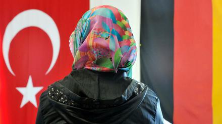 Eine Frau sitzt in der Ditib-Moschee im hessischen Friedberg vor einer türkischen und einer deutschen Fahne. 