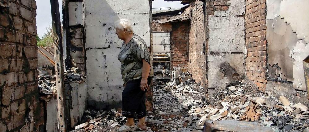 Eine Frau steht in den Trümmern ihres zerstörten Hauses in einem Dorf in der Nähe von Donezk. 