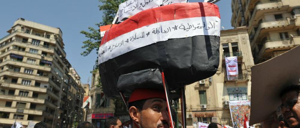 Dieser Demonstrant hat sich ein Schiff aus Pappe in den Farben Ägyptens auf den Kopf geschnallt. „Wir müssen wieder auf den richtigen Kurs“, sagt er. 