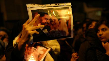 Eine Demonstrantin zeigt das Foto eines frisch verheirateten Paares, das beim Absturz starb. 