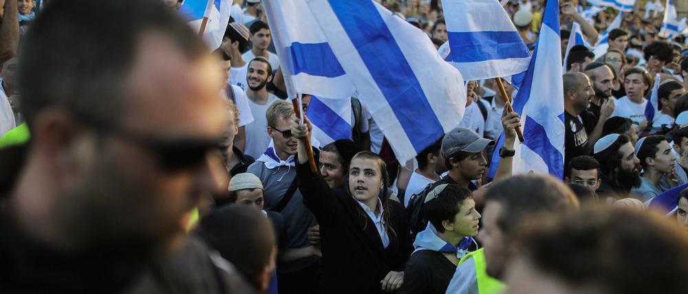 Menschen schwenken bei dem von rechtsgerichteten Nationalisten in Israel organisierten Flaggenmarsch Nationalflaggen.