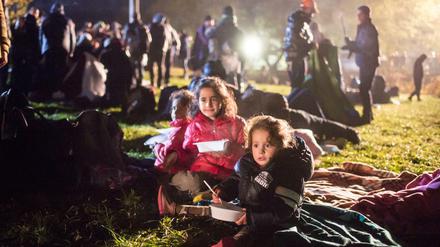 Flüchtlingskinder essen am Mittwoch auf einer Wiese an der deutsch-österreichischen Grenze in Österreich vor Wegscheid und warten auf ihre Einreise nach Deutschland. 