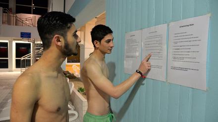 Es ist nie zu spät. Zwei nasse Flüchtlinge beim Studium der Baderegeln. 