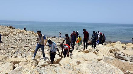 Gerettete Flüchtlinge gehen an der Küste östlich von Tripolis an Land, doch rund 100 Flüchtlinge werden noch vermisst. Am Sonntag kam es zu einem weiteren Bootsunfall. 