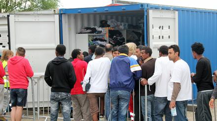 Flüchtlinge stehen in der Erstaufnahmeeinrichtung im nordhessischen Calden vor einem Container, aus dem Spenden ausgegeben werden. 