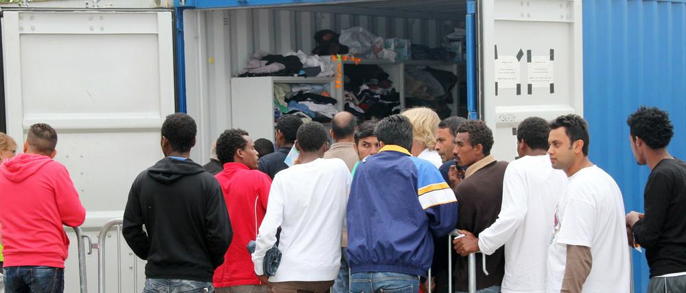 Flüchtlinge stehen in der Erstaufnahmeeinrichtung im nordhessischen Calden vor einem Container, aus dem Spenden ausgegeben werden. 