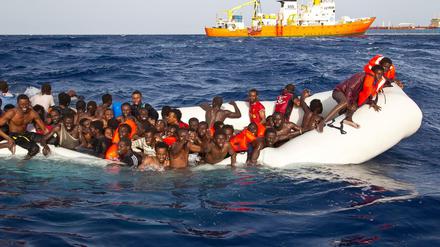 Flüchtlingsboot im Mittelmeer, im Hintergrund Helfer von SOS Mediterranee