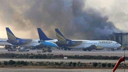 Flammen und Rauch steigen aus einem Gebäude des Flughafens von Karachi auf.
