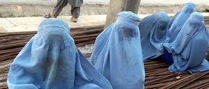 In Burkas gekleidete Frauen sitzen in Herat (Afghanistan) auf Metallstangen.