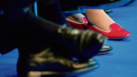 Die roten Schuhe einer Teilnehmerin des Tages der Industrie sind am 11.06.2013 in Berlin zwischen den Beinen von Männern in dunklen Anzügen und passendem Schuhwerk zu sehen. Die 30 Dax-Konzerne sind nach einem Bericht des Arbeitgeberverbandes BDA von ihren selbst gesteckten Zielen für mehr Frauen in Spitzenpositionen teils noch weit entfernt. 