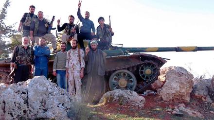 Rebellen der Freien Syrischen Armee posieren vor einem Panzer.
