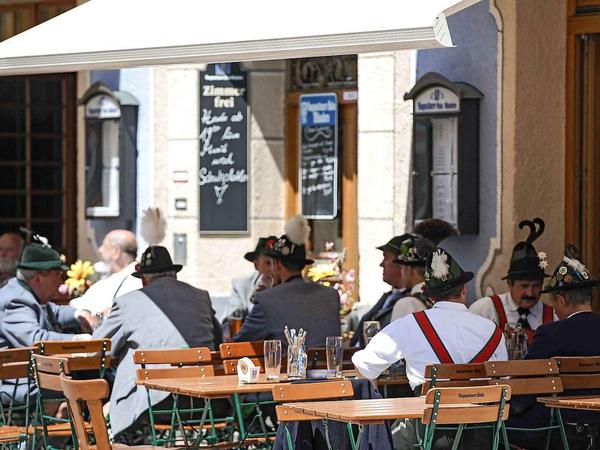 Idylle in Garmisch Partenkirchen. Männer in bayerischer Tracht sitzen sitzen in der Altstadt vor einem Gasthof und trinken Bier.