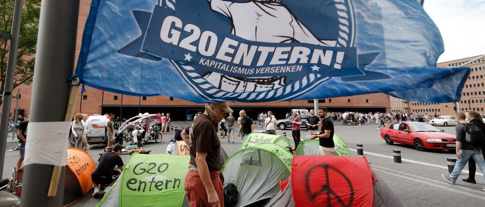 Eine Fahne mit der Aufschrift "G20 entern" weht in Hamburg vor der Elbphilharmonie über einem kleinen Zeltlager von G-20-Gegnern.