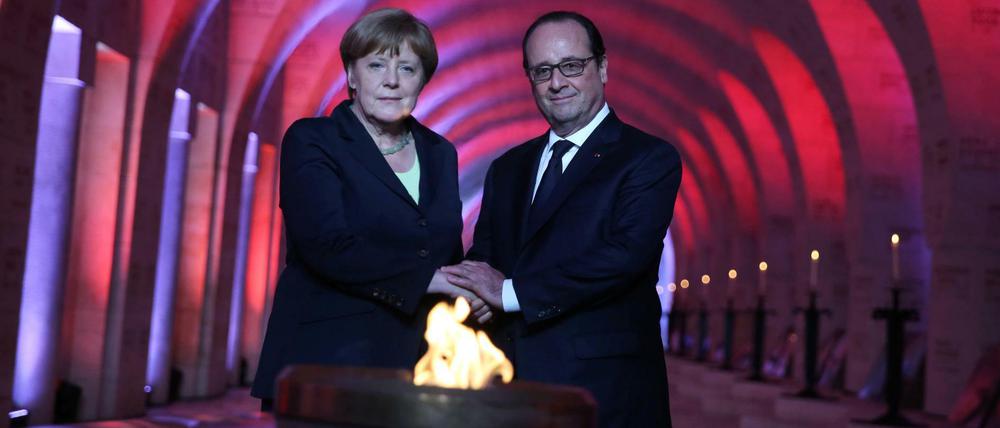 Der französische Präsident Francois Hollande und Bundeskanzlerin Angela Merkel (CDU) entzünden gemeinsam die Flamme in der Nationalnekropole Douaumont bei Verdun.