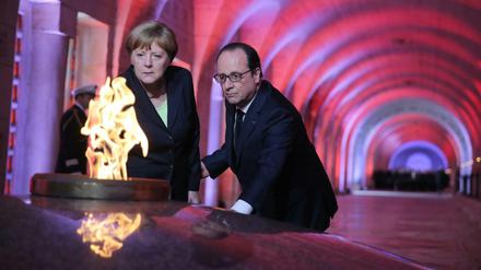Der französische Präsident Francois Hollande und Bundeskanzlerin Angela Merkel entzünden gemeinsam die Flamme in der Nationalnekropole Douaumont bei Verdun. 