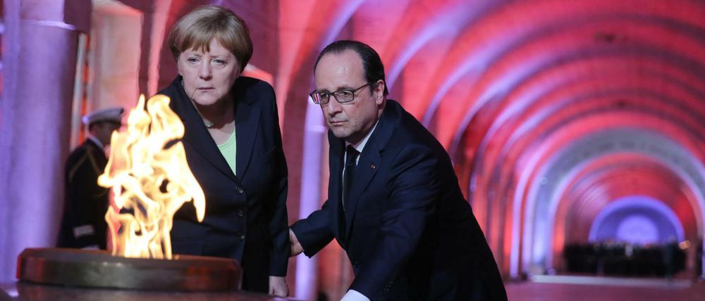 Der französische Präsident Francois Hollande und Bundeskanzlerin Angela Merkel entzünden gemeinsam die Flamme in der Nationalnekropole Douaumont bei Verdun. 