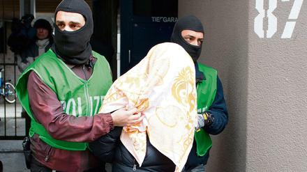 Polizisten führen bei einer Razzia gegen Islamisten am 04.02.2016 in Berlin einen mit einem Tuch verdeckten Verdächtigen ab. 