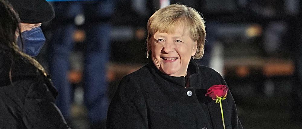 Angela Merkel nach ihrer Verabschiedung mit einer Rose in der Hand neben ihrem Mann, Joachim Sauer.
