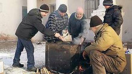 Am offenen Feuer kochen Bewohner der Stadt Mironowka. 