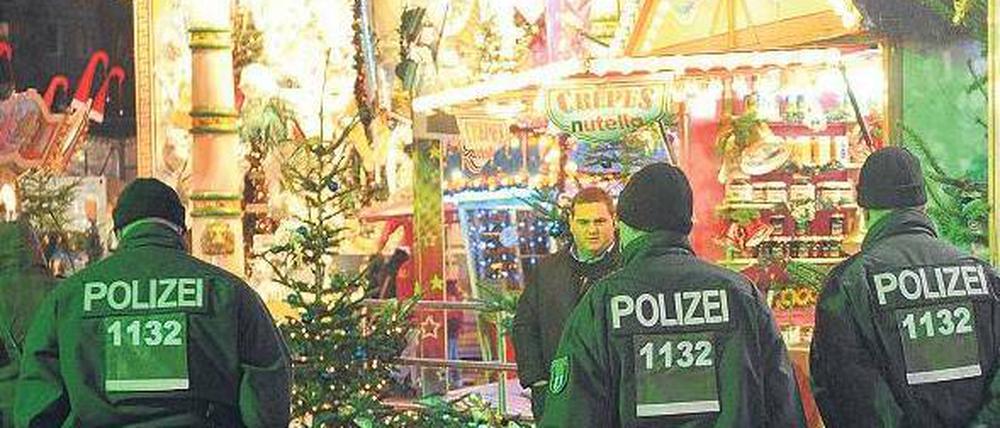 Grüne Weihnachten. Polizeibeamte gehen auf einem Weihnachtsmarkt in der Nähe des Alexanderplatzes in Berlin entlang. 