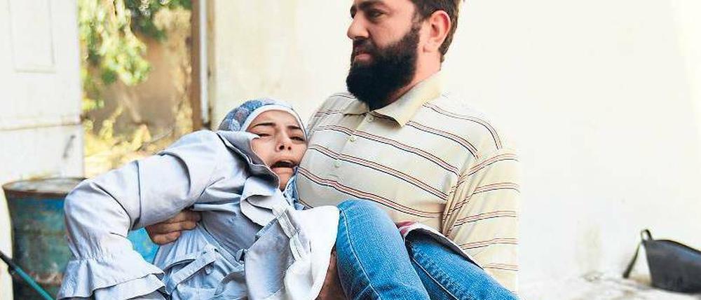 Erste Hilfe: Ein Kämpfer der „Freien Syrischen Armee“ bringt ein verletztes Mädchen in Sicherheit. Hubschrauber und Kampfflugzeuge der Armee bombardieren die nordsyrische Stadt Aleppo, die seit fünf Tagen heftig umkämpft ist. 
