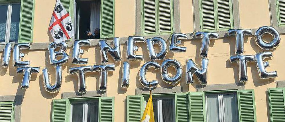 Willkommensgruß. In Castel Gandolfo, wo Benedikt XVI. in der päpstlichen Sommerresidenz die kommenden Wochen verbringen wird, ist ein Haus mit Ballons geschmückt – und dem Schriftzug „Benedikt, alle sind mit dir“. Foto: Vincenzo Pinto/AFP