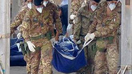 Tod vor Lampedusa. Italienische Soldaten tragen die Leiche eines Opfers. Foto: AFP