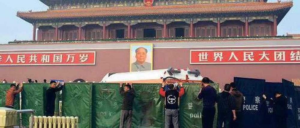 Verdeckt: Der Ort des Unfalls auf dem Platz des Himmlischen Friedens in Peking wird von Arbeitern und Polizisten abgesperrt. Auf dem Tiananmen-Platz hatten Sicherheitskräfte im Juni 1989 ein Massaker an friedlichen Demonstranten verübt. Foto: Ed Jones/AFP