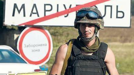 Wer hat das Sagen in der Stadt? Ein ukrainischer Soldat steht vor einem Ortsschild der ostukrainischen Hafenstadt Mariupol. 