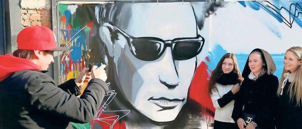 Popstar Putin. Junge Besucher einer Cartoon-Ausstellung vor einem Wandbild in Moskau. 