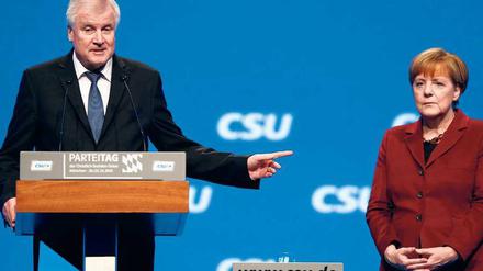 Wer gibt uns die Obergrenze nicht? Horst Seehofer beharrt auf seiner Position in der Flüchtlingsfrage, Angela Merkel steht regungslos daneben. 
