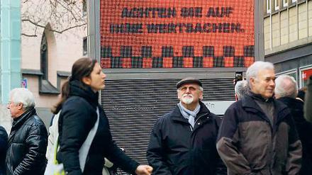 Ein Plakat weist in der Kölner Innenstadt Passanten auf die Gefahr durch Taschendiebe hin. 