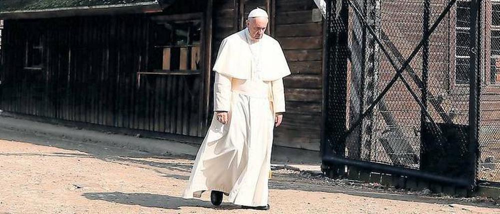 Papst Franziskus durchschreitet schweigend in der KZ-Gedenkstätte Auschwitz-Birkenau das Lagertor mit der zynischen Aufschrift „Arbeit macht frei“.