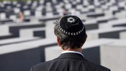 Eine Jude mit der traditionellen Kopfbedeckung Kippa und einem Davidstern auf dem Gelände des Holocaust Mahnmals in Berlin.