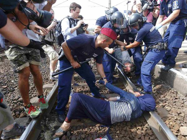 Die ungarische Polizei nimmt Flüchtlinge aus einem angehaltenen Zug fest. 