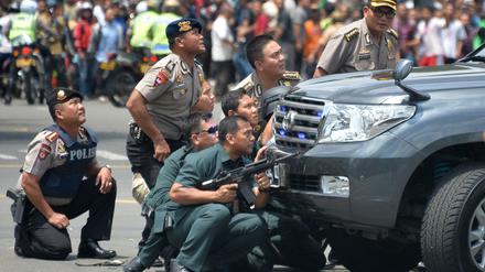Polizisten suchen Schutz hinter einem Fahrzeug in der indonesischen Hauptstadt Jakarta.
