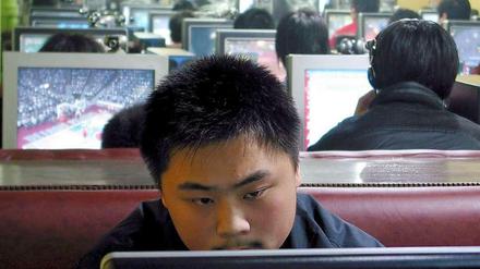 Ein Mann sitzt in einem Internet-Cafe in Qingdao in China an einem Computer.