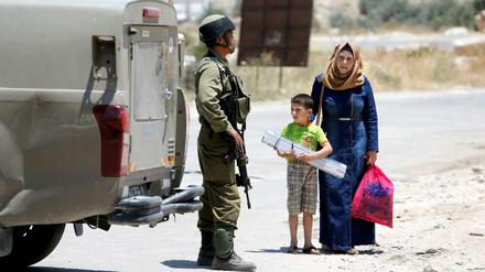 Ein israelischer Soldat stoppt eine Palästinenserin und ihr Kind in der Nähe von Jatta.
