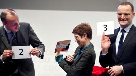 Friedrich Merz (alle CDU,l-r), Annegret Kramp-Karrenbauer und Jens Spahn stehen nebeneinander auf der Bühne und halten Zettel für die Reihenfolge der Vorstellung in der Hand. 