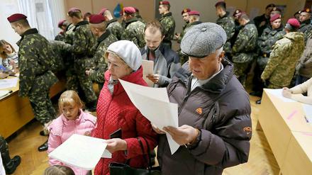 Eine Familie und ziemlich viele Soldaten bei der Abstimmung in einem Wahllokal in Kiew.