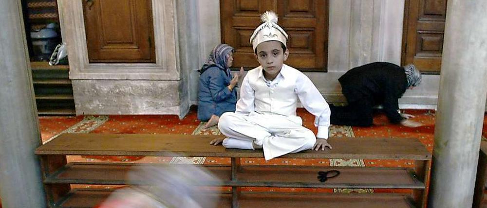 Ein türkischer Junge sitzt vor der Beschneidungszeremonie im traditionellen Gewand in einer Moschee. 