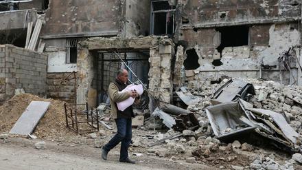 Das im Januar 2017 aufgenommene Foto zeigt einen Mann, der mit seinem Kleinkind im östlichen Stadtteil Salaheddine in der vom Krieg zerstörten Stadt Aleppo unterwegs ist.