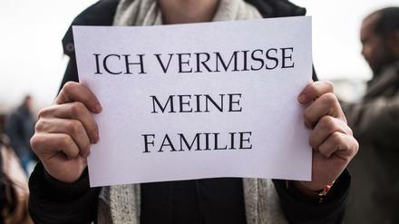 Ein Mitglied des Flüchtlingsrats Berlin weist mit einem Schild auf die emotionale Bedeutung des Familiennachzugs hin.
