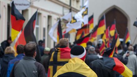 Ein Mann hat eine Fahne mit Logo der Identitären Bewegung geht im Rahmen einer Kundgebung vom Kornmarkt in Bautzen (Sachsen) durch die Innenstadt.