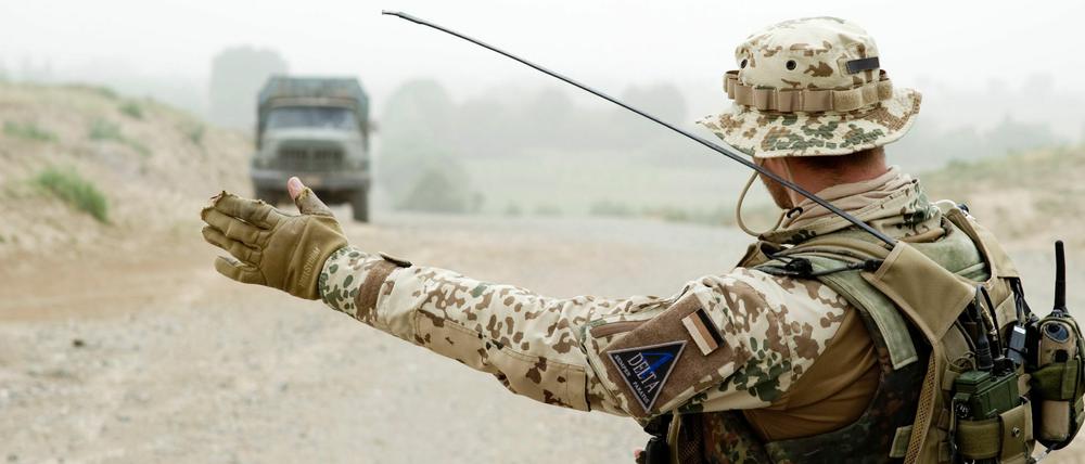 Ein Soldat der Bundeswehr weist wenige Kilometer westlich von Kundus in Afghanistan während eines Einsatzes an einer Straßensperrung einem Lkw den Weg.