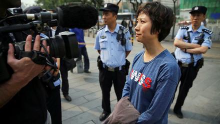Umringt von Polizei und Zivilbeamten spricht Lin Ru nach dem Urteil gegen ihren Mann, den Menschenrechtsanwaltes Xia Lin, vor dem Gerichtsgebäude in Peking zu den Medien. 