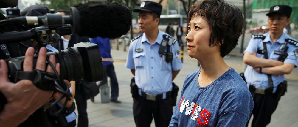 Umringt von Polizei und Zivilbeamten spricht Lin Ru nach dem Urteil gegen ihren Mann, den Menschenrechtsanwaltes Xia Lin, vor dem Gerichtsgebäude in Peking zu den Medien. 