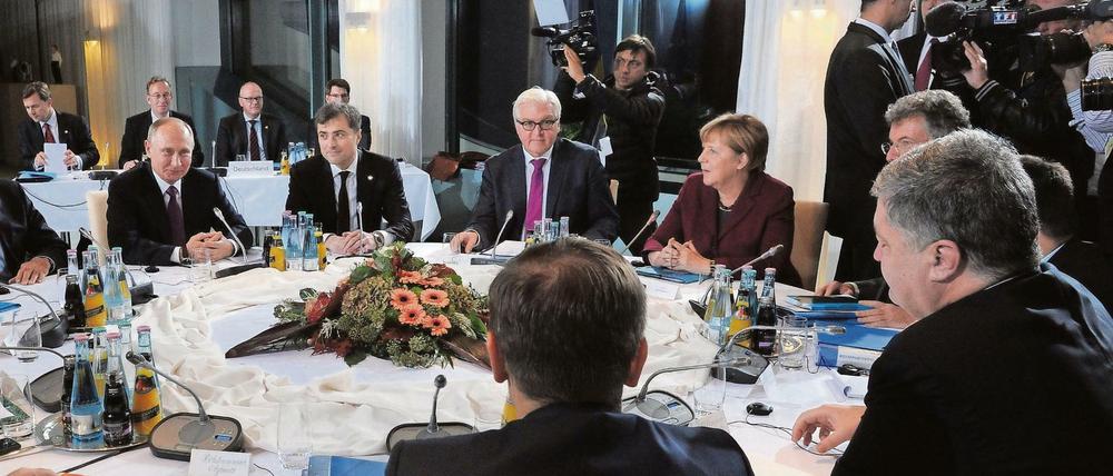 Krisengespräche am runden Tisch in Berlin, mit Wladimir Putin (l.) und Petro Poroschenko (vorn r.).